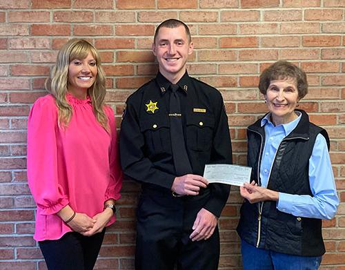 Verna Feather, Recruit Aaron Pacos, and Raechel Waid stand together, holding scholarship check